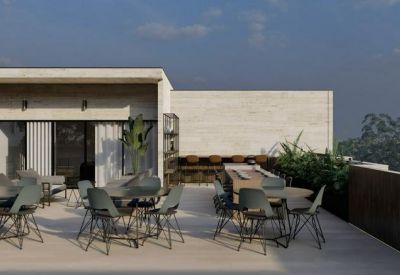 Rooftop dining area with several tables, chairs, and potted plants under a clear sky.