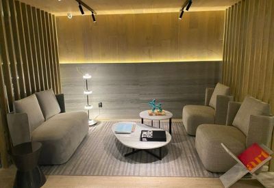 Cozy communal lounge with grey sofas, wooden slat walls, and warm accent lighting.