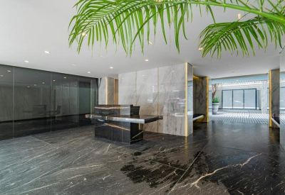 Sleek modern reception lobby with polished dark marble floors and a stone front desk.