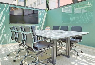 Bright glass-walled meeting room with mint green walls and a large conference table.