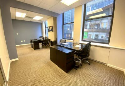 Private office suite with dark wood desks and large windows overlooking the city.