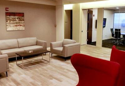 Bright lounge area with grey sofas, a coffee table, and red accent chairs.