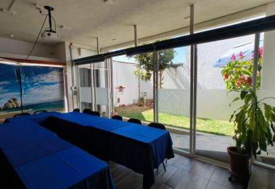 Bright meeting room with blue tables and large glass doors opening to a garden.