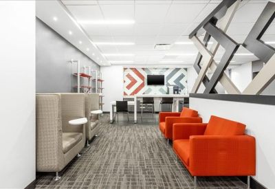 Vibrant communal lounge area with bright orange armchairs and geometric wall art.