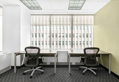 Spacious three-person workstation area with ergonomic chairs and city views.