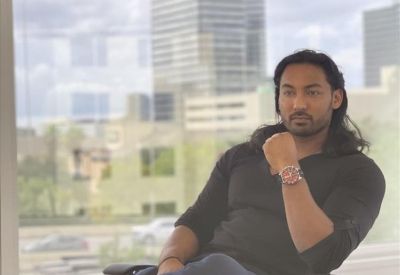 Man sitting in a professional office chair with a city skyline background.