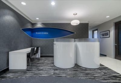 Minimalist lobby area with sleek white curved reception pods and grey textured walls.