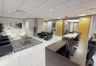 Spacious reception lobby with a dark wood front desk, lounge seating, and geometric rug.