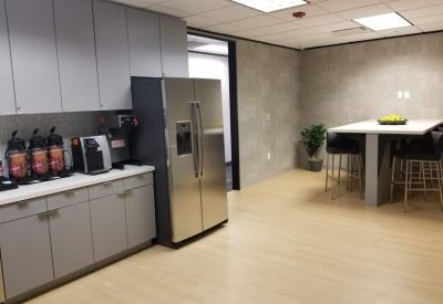 Kitchenette and dining area with grey cabinetry, a stainless steel fridge, and high-top table.