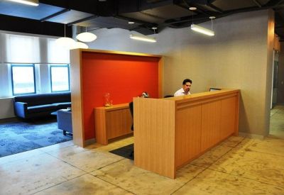 Reception area with a light wood desk and a bright orange feature wall.