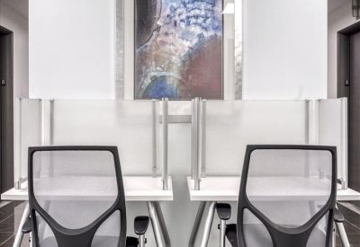 Symmetric dual workstation with mesh chairs and abstract art piece.