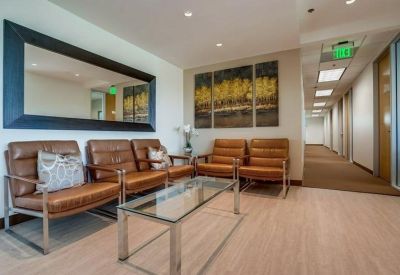 Lounge area with brown leather armchairs, a glass coffee table, and a large mirror.