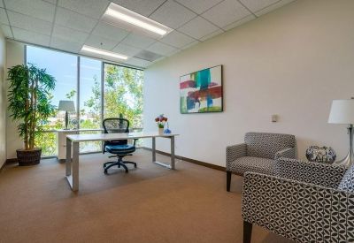 Private office with a white desk, leather armchairs, and abstract wall art.