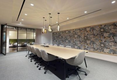 Professional boardroom with a long white table and a decorative patterned feature wall.