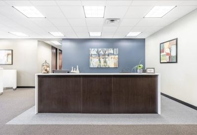 Reception area featuring a dark wood desk against a slate blue wall with framed art.