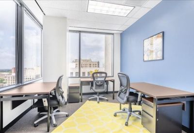 Bright multi-person office suite featuring a blue accent wall and yellow area rug.
