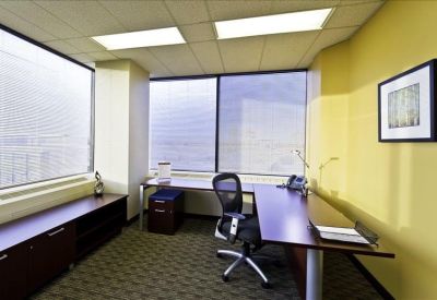 Windowed corner office with a dark wood desk and city views.