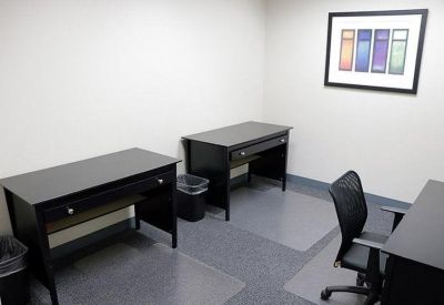 Internal three-person office suite with black desks and a colorful framed print.