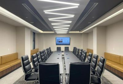 Large executive boardroom featuring a long dark table and zigzag ceiling lights.