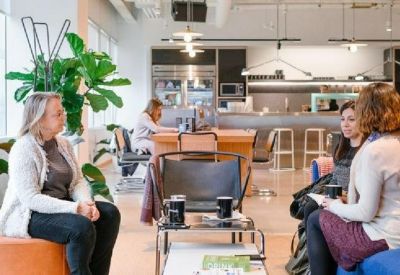 Lounge area with blue and orange seating, featuring coffee tables and indoor plants.