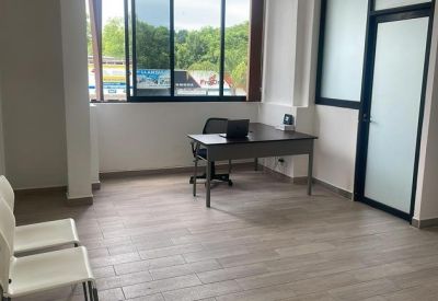Bright corner office showing a desk with a laptop and white chairs.