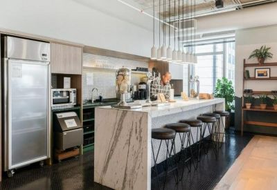 Bright kitchen and break area with a marble island, bar stools, and modern appliances.