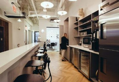 Modern communal kitchen with wooden herringbone floors, breakfast bar, and stainless steel appliances.