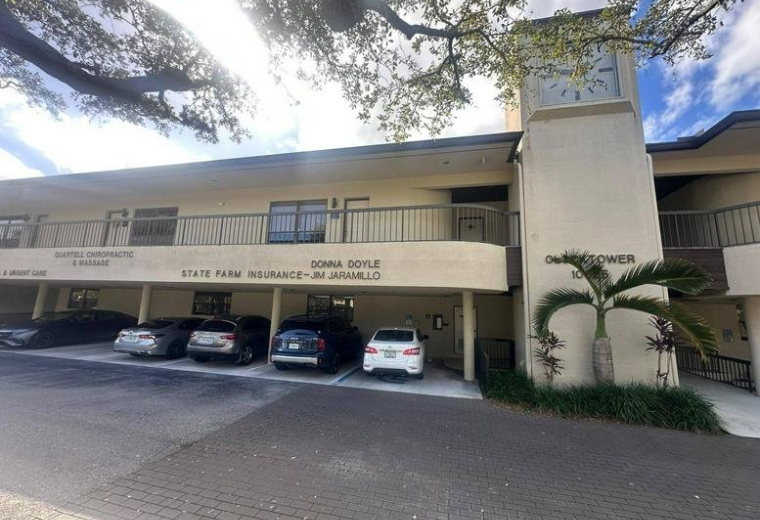 Exterior view of the office building at 10625 North Military Trail showing the parking area and clock tower.