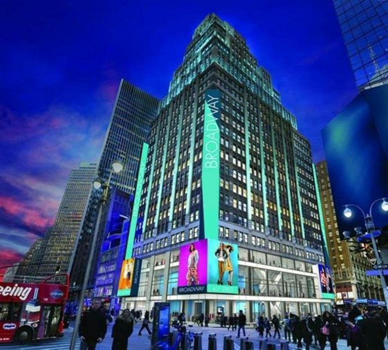 Night view of the 1441 Broadway skyscraper with vibrant digital billboards at its base.