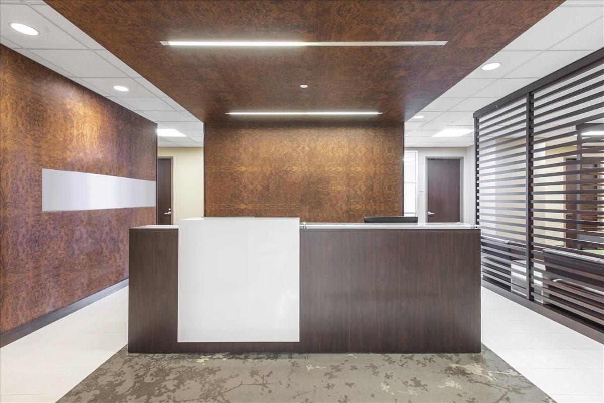 Reception desk with a minimalist white and dark wood design and feature ceiling.