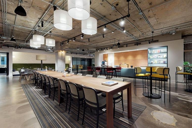 Spacious communal dining area at 311 West Monroe Street with industrial ceilings and long wooden tables.