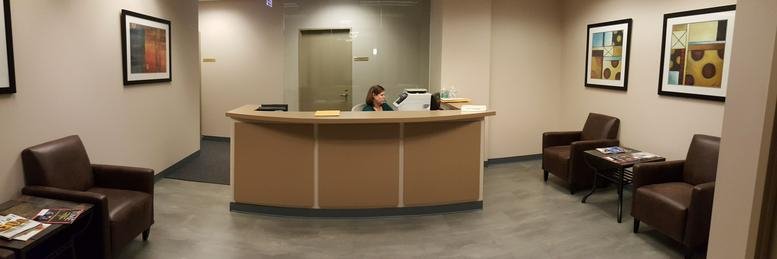 Professional reception area with a curved wooden desk and leather armchairs.