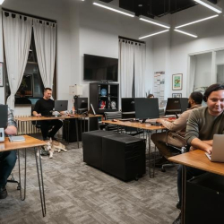 Spacious open office area with multiple workstations and modern track lighting.