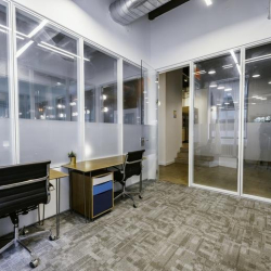 Modern glass-walled office workspace with blue-accented filing cabinets.