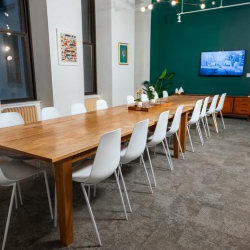 Large meeting room with a long timber table, white chairs, and a green feature wall.