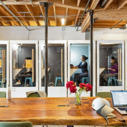 Private glass-enclosed phone booths for focused work.