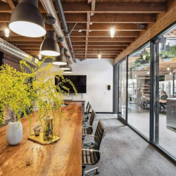 Long wooden conference table beside an exposed brick wall with industrial lighting.