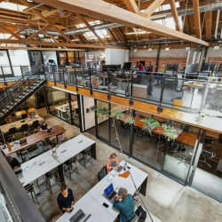 High-angle view from the mezzanine overlooking glass-walled offices and desks.