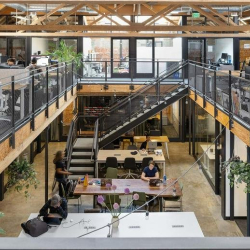 Wide-angle view of the industrial-style office with exposed wooden trusses.