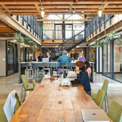 Mezzanine workspace featuring desks and bright light from overhead skylights.