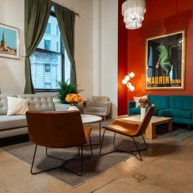 Stylish lounge area at 26 Broadway with a red accent wall and mid-century modern furniture.. Click for details.