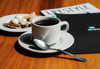 Close-up of a coffee cup and pastries on a wooden desk.
