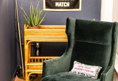 Cozy corner with a green velvet armchair, a wicker bar cart, and a blue accent wall.