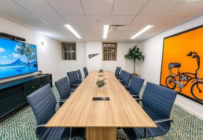 Long wooden boardroom table with blue chairs and a vibrant orange bicycle mural.