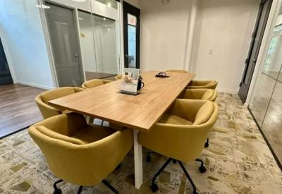 Small meeting room with yellow velvet chairs and glass walls.