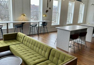 Coworking space featuring a green sectional sofa and high-top tables.