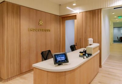 Modern reception desk with wood-paneled walls and the Industrious logo.