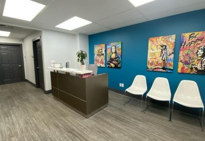 Reception desk with vibrant pop art and white waiting chairs.