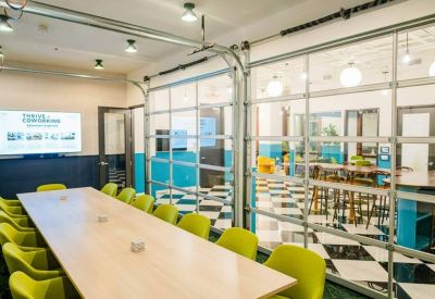 Meeting room with a long wooden table and lime green chairs separated by glass garage doors.