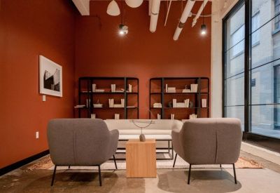 Modern lounge area with terracotta walls, grey armchairs, and built-in bookshelves.